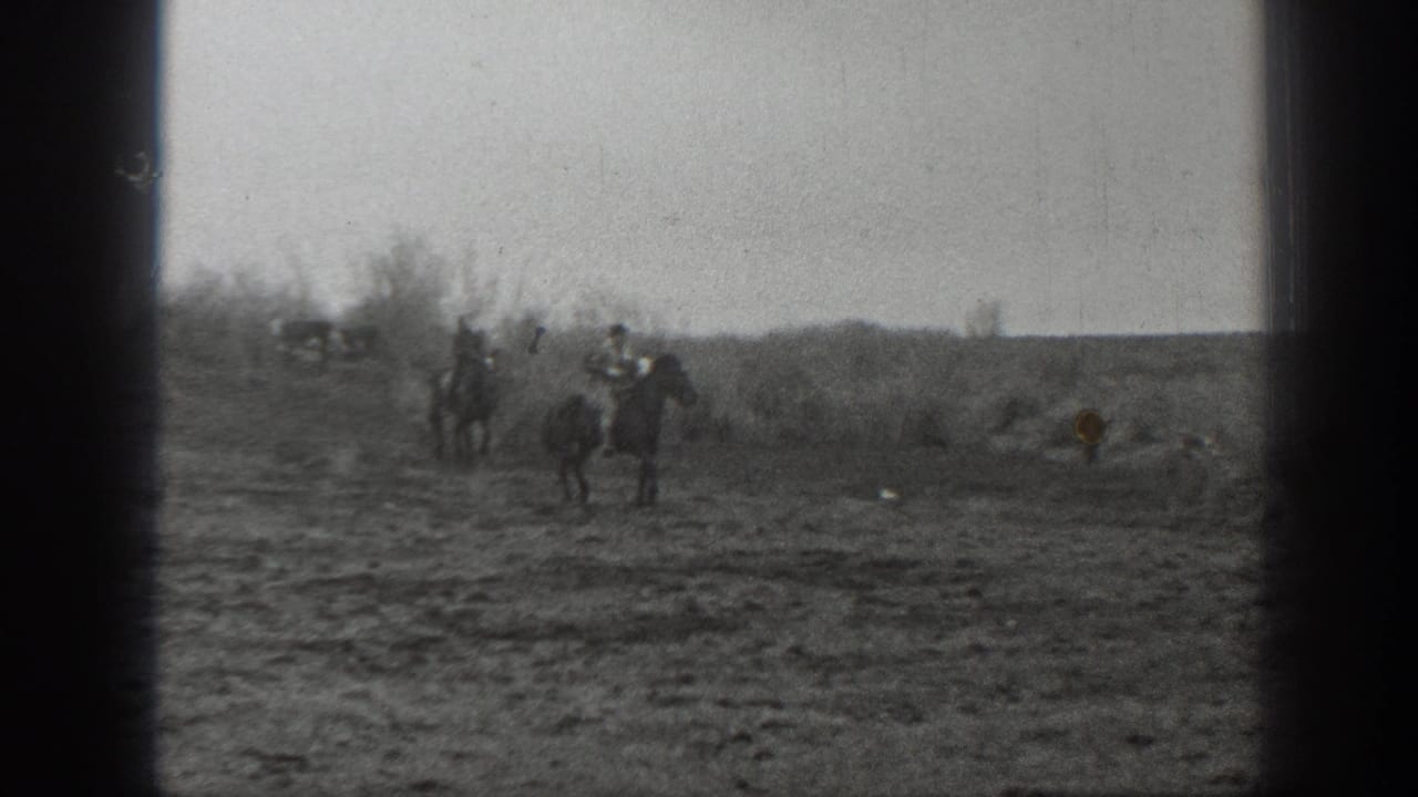 1939 Montana 8mm frame showing distant horseback riders and cattle spread across open prairie under a pale sky.