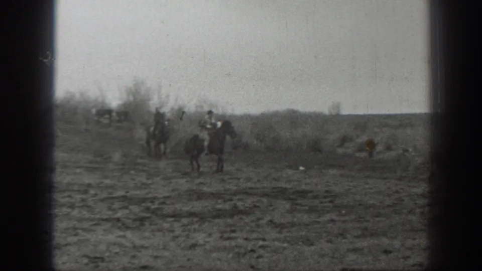 1939 Montana 8mm frame showing distant horseback riders and cattle spread across open prairie under a pale sky.
