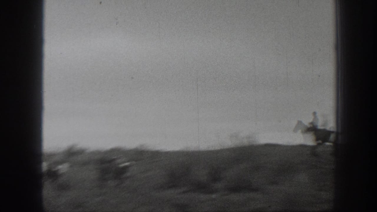 1939 Montana 8mm frame with a lone rider on horseback near the right edge of a low, brushy prairie horizon.
