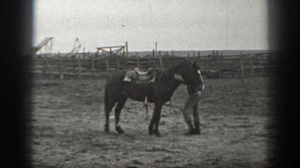 The man gently pets or steadies the saddled horse near its neck in the 1939 Montana ranch scene.