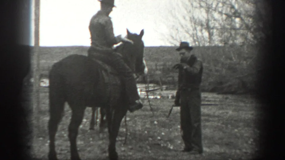 1939 Montana ranch footage shows a man on horseback near another man standing with a lead or reins in an open field.