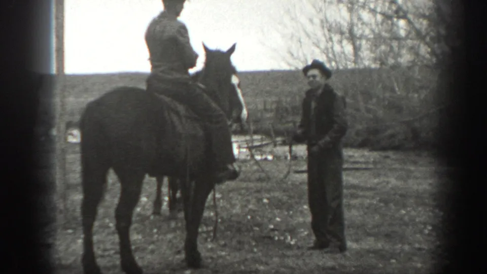 A rider on horseback stands near a man holding a lead or reins in black-and-white 1939 Montana ranch footage.