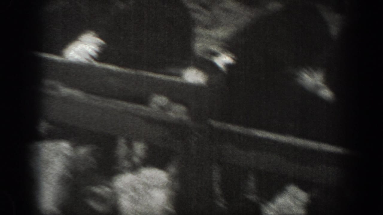 Montana 1939 home-movie frame with a blurred person or hands near a rail above a rural farm scene.