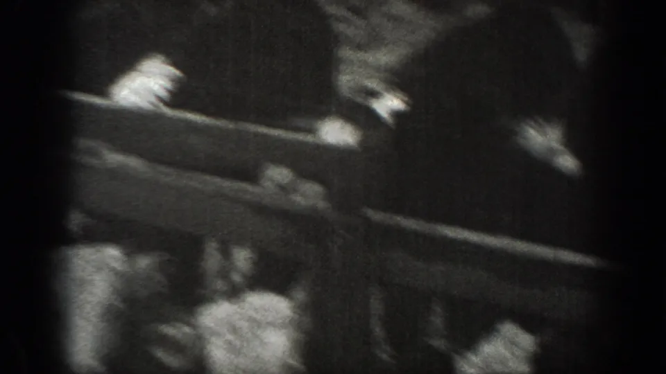 Montana 1939 home-movie frame with a blurred person or hands near a rail above a rural farm scene.
