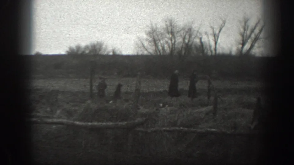 1939 Montana 8mm frame showing distant farm figures, small animals, fencing, and leafless trees across open land.
