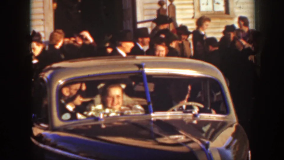 At the Montana wedding, the couple sits in the decorated car while guests outside the church appear to wave and celebrate.