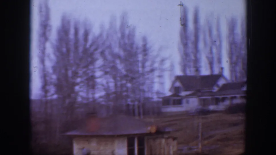 1939 Montana farm buildings and tree rows appear across a soft, scratched 8mm frame.