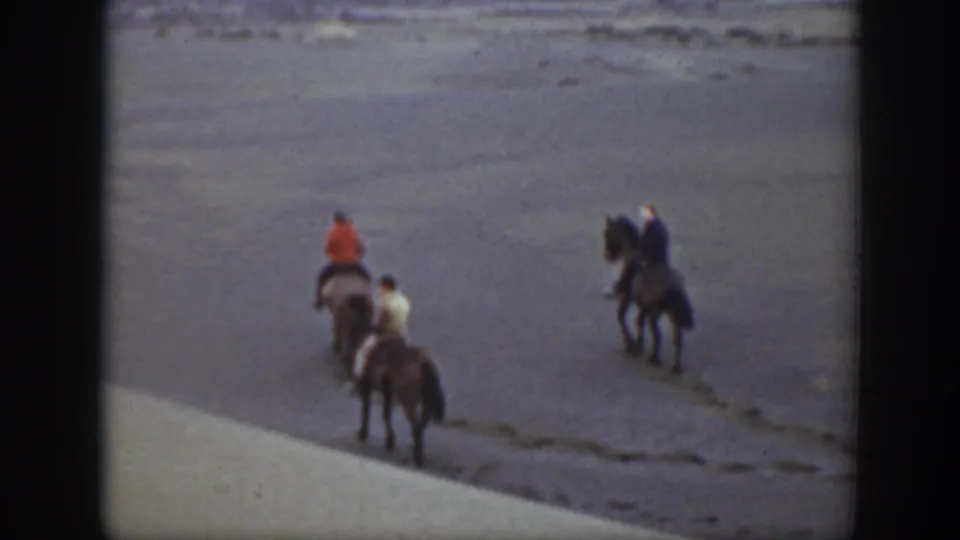 Four horseback riders, including one in an orange jacket and one in a light coat, move across open Montana terrain in 1939 footage.