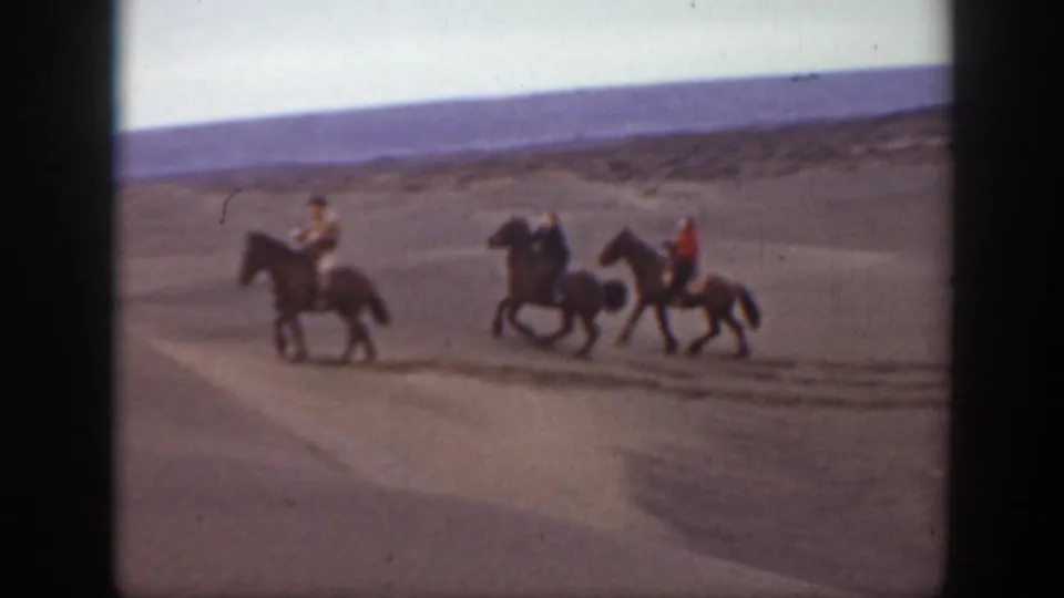 Three horseback riders, including one in a red garment, pass across the 1939 Montana home-movie frame on arid terrain.