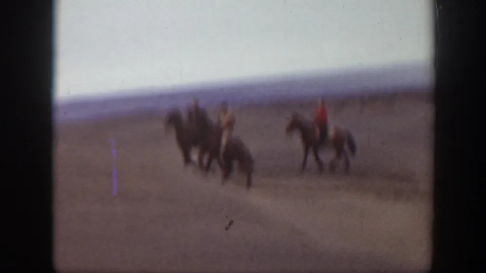 The riders become motion-blurred as they continue across the open Montana landscape, with 8mm color fade and gate edges visible.