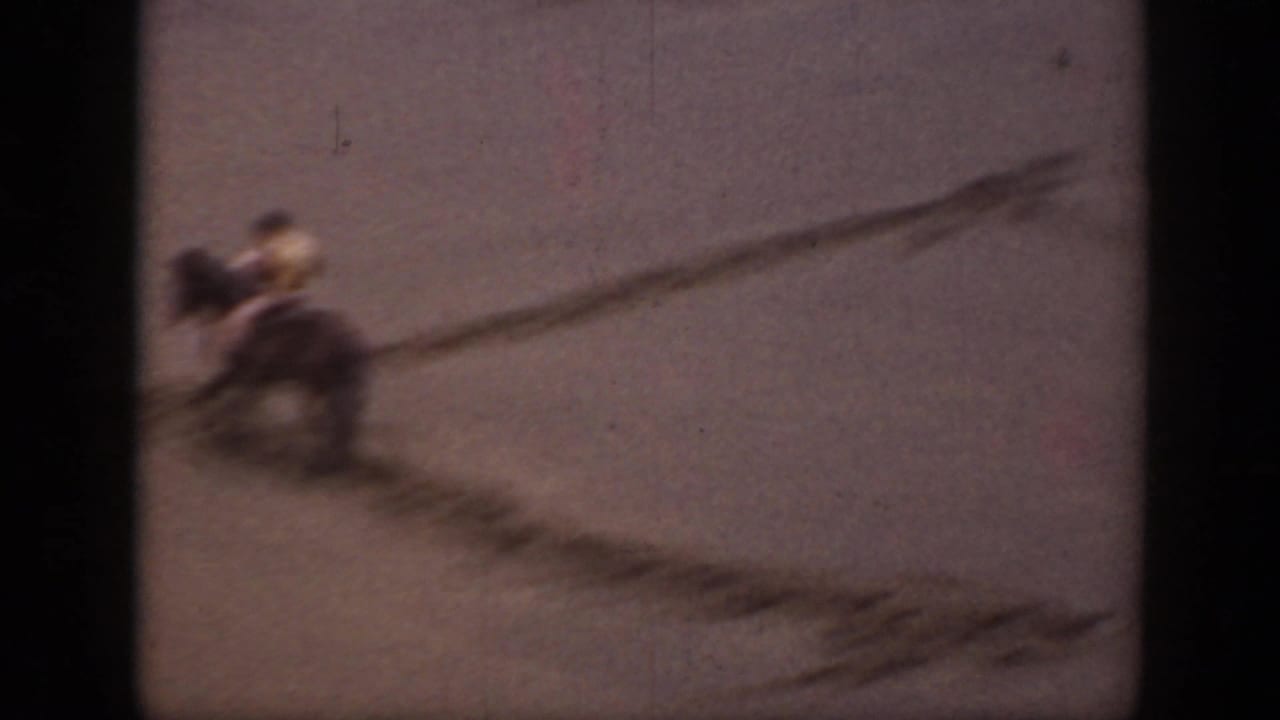A distant rider on horseback moves through the sandy Montana landscape, with blur and dark dune markings across the frame.