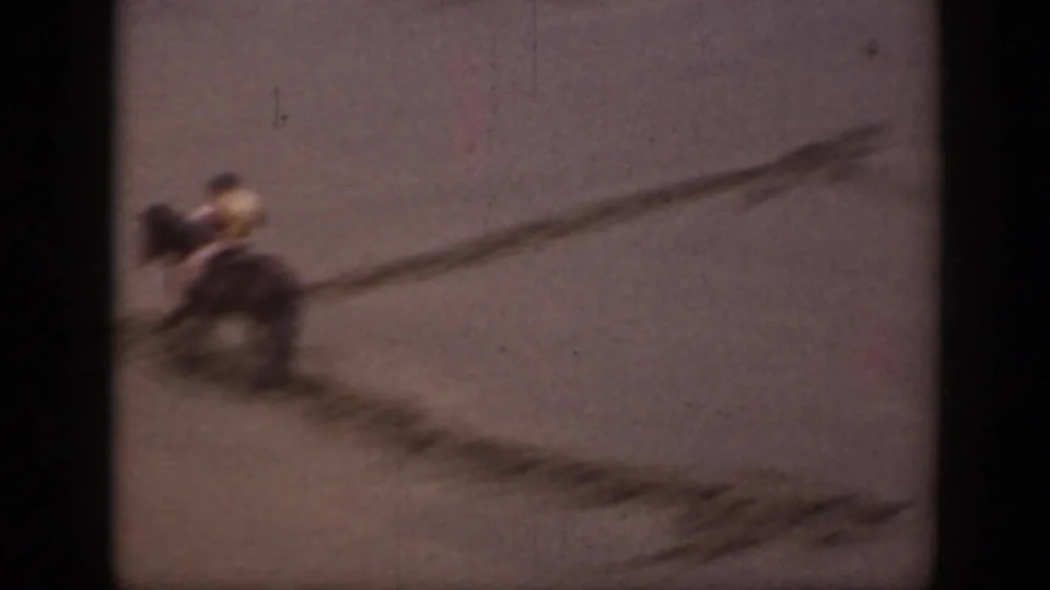 A distant rider on horseback moves through the sandy Montana landscape, with blur and dark dune markings across the frame.