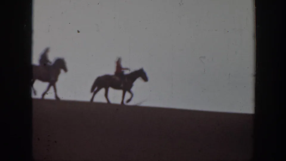 Near the end of the Montana 8mm shot, two mounted riders remain visible as silhouettes along the sloped hilltop.