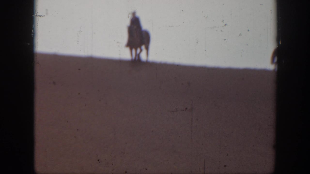 1939 Montana frame with a single distant mounted rider silhouetted on the crest of a sand dune.