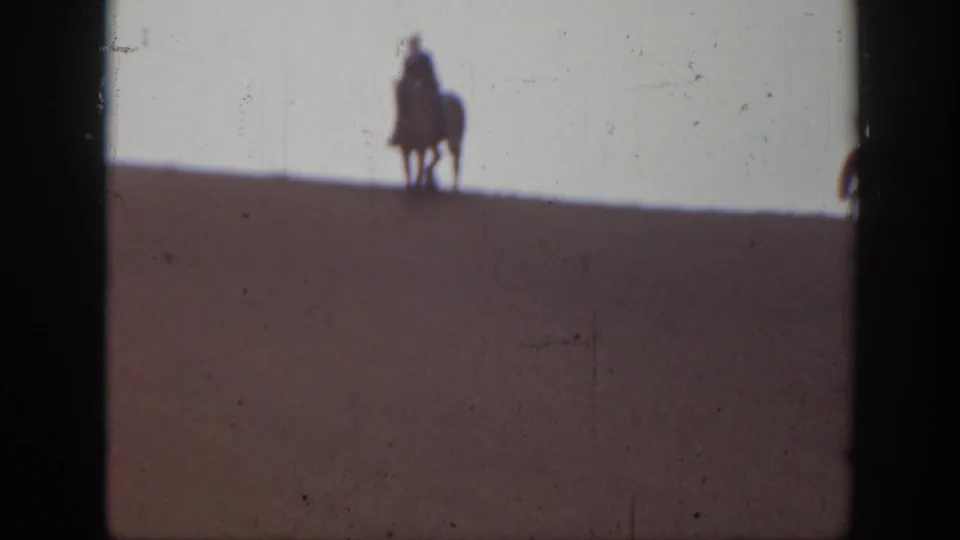 1939 Montana frame with a single distant mounted rider silhouetted on the crest of a sand dune.