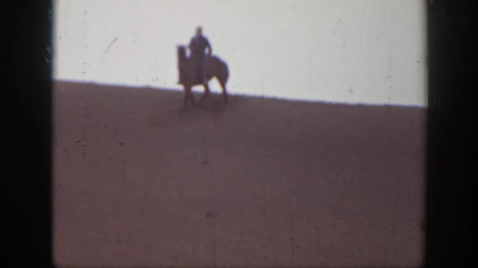 Distant horseback rider on a Montana sand dune in a soft, high-contrast 1939 home-movie frame.