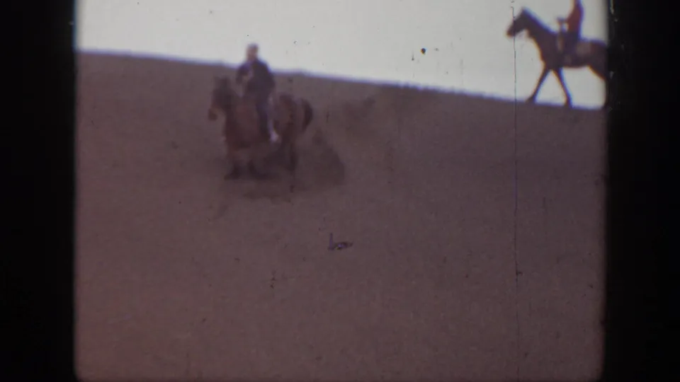 1939 Montana dune scene with a central mounted rider and another horse partly visible at the right edge.