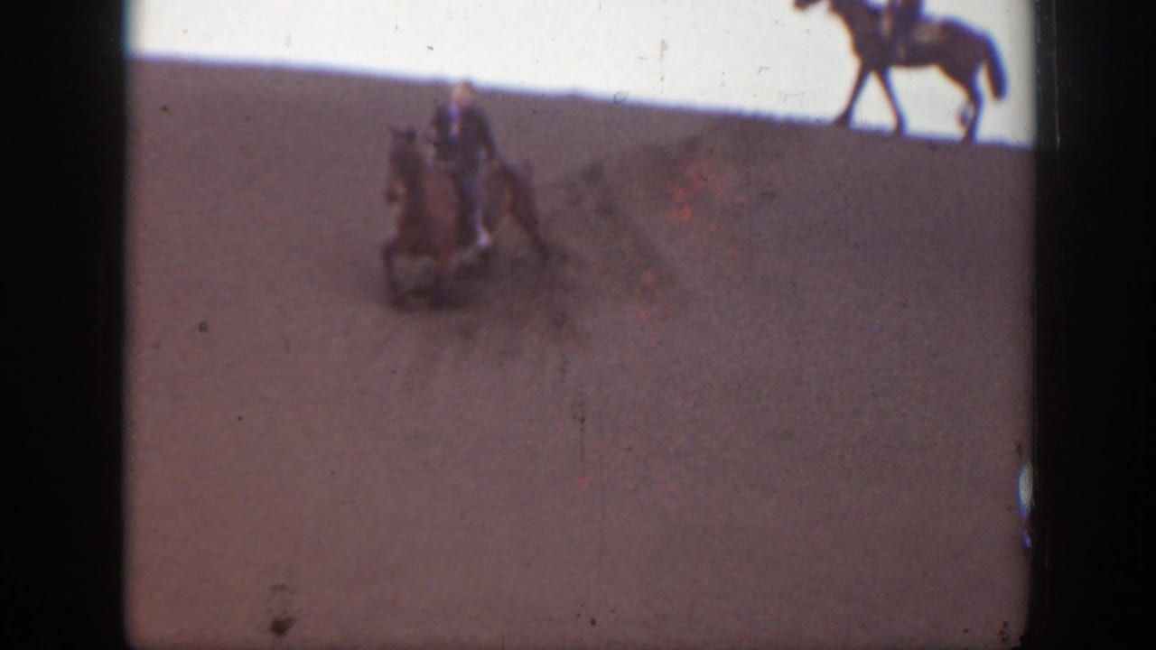 1939 Montana 8mm frame showing riders on horseback at a distance across a dry, open landscape with visible film edge marks.