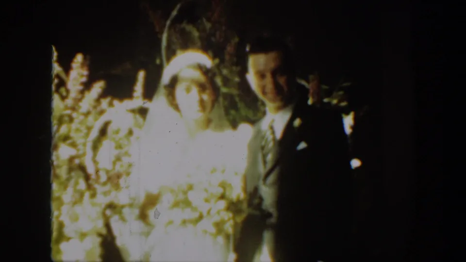 The bride and groom appear together in the 1939 Montana wedding footage, softly focused and surrounded by floral decor.