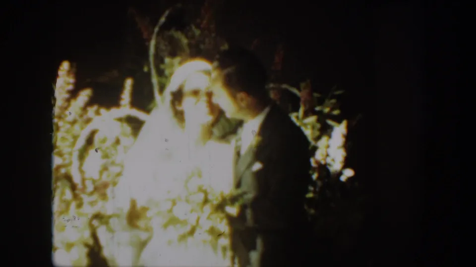 In this 1939 Montana wedding moment, the groom turns toward the veiled bride while they stand close together in soft 8mm light.