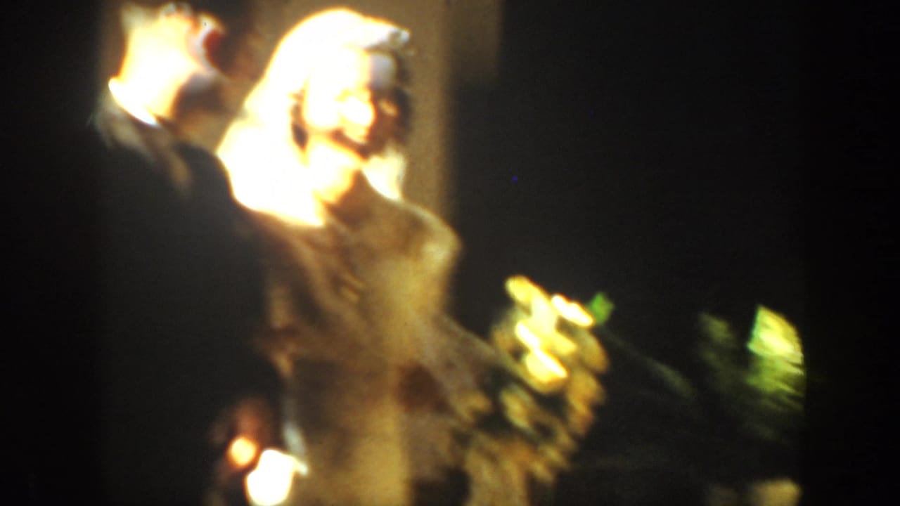 Bride and groom kissing under warm light with flowers nearby.