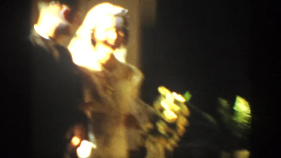 Bride and groom kiss under warm, overexposed light in the Montana wedding footage, with floral arrangements at the side.