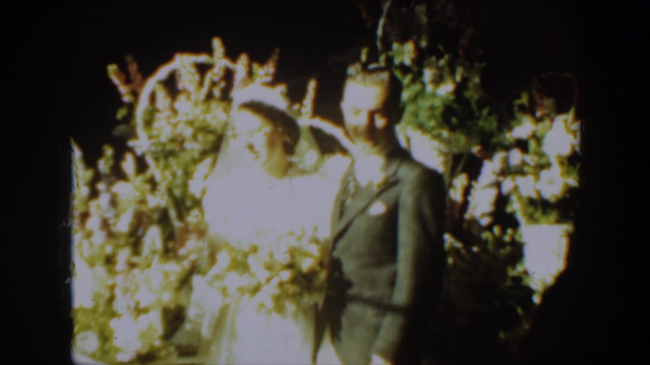 A bride in a white gown and veil stands beside a groom in a suit during a 1939 Montana wedding home movie.