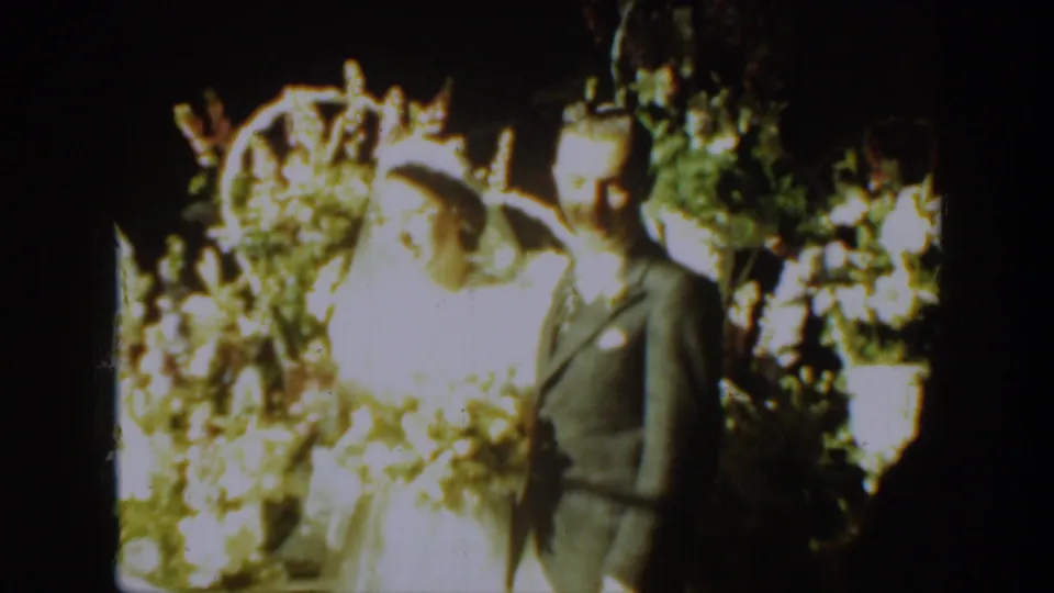 A bride in a white gown and veil stands beside a groom in a suit during a 1939 Montana wedding home movie.