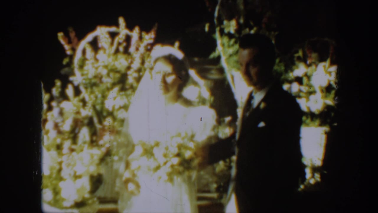 Bride and groom facing the camera beside wedding flowers.