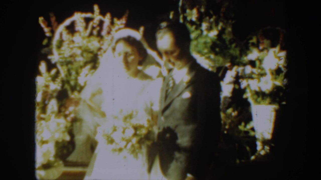 1939 Montana wedding frame showing the bride smiling beside the groom under a bright floral arch.