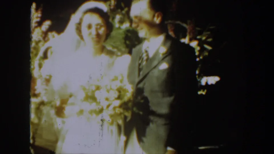 1939 Montana home-movie frame with the bride facing camera and the groom turned toward her at the ceremony.