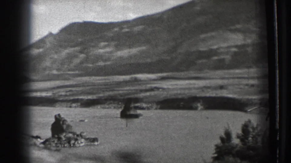 1939 Washington home-movie frame with a closer mountain backdrop, water in front, and a dark ambiguous shape rising near the foreground shoreline.