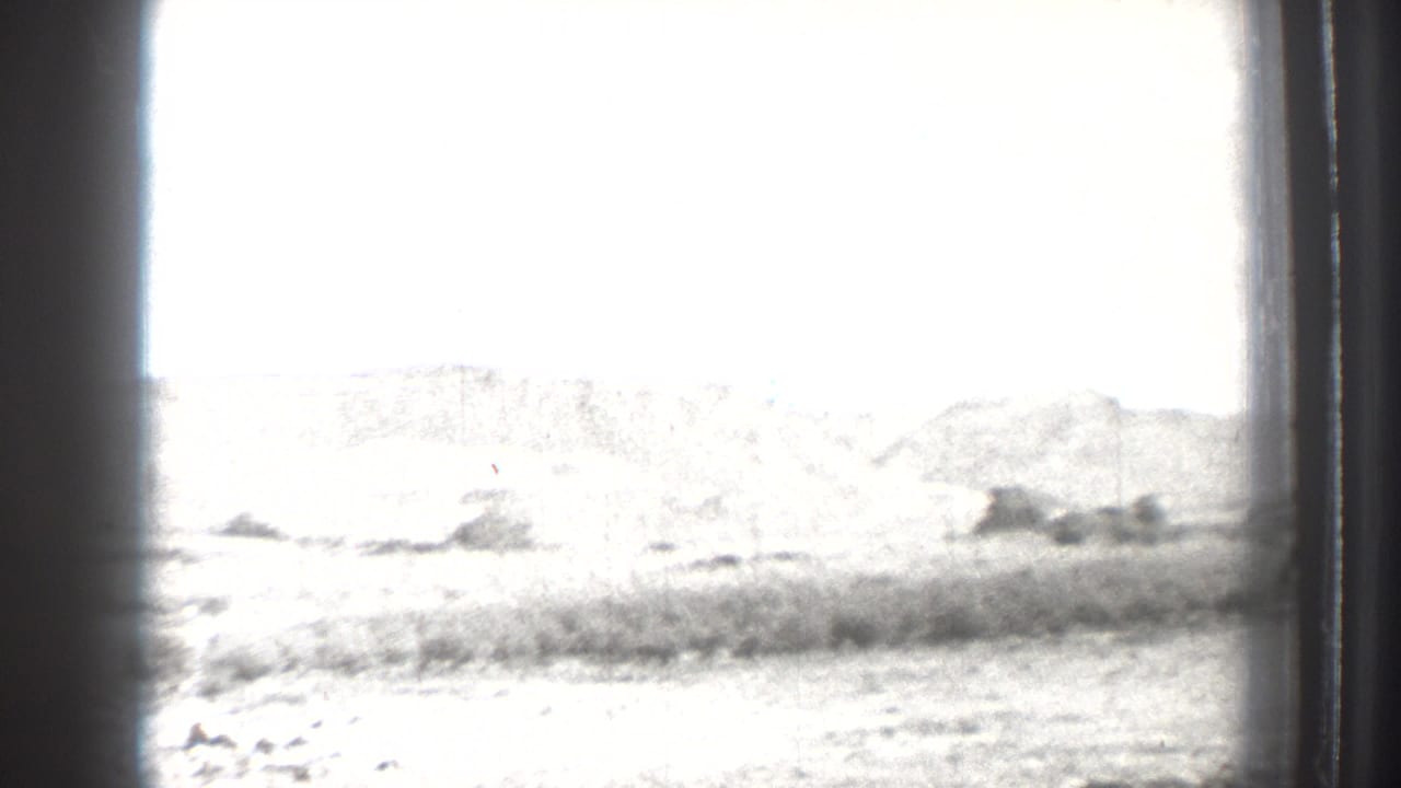 1939 Washington 8mm frame showing a bright lakeside landscape with scrub and distant hills, partly obscured by the film or window edge.
