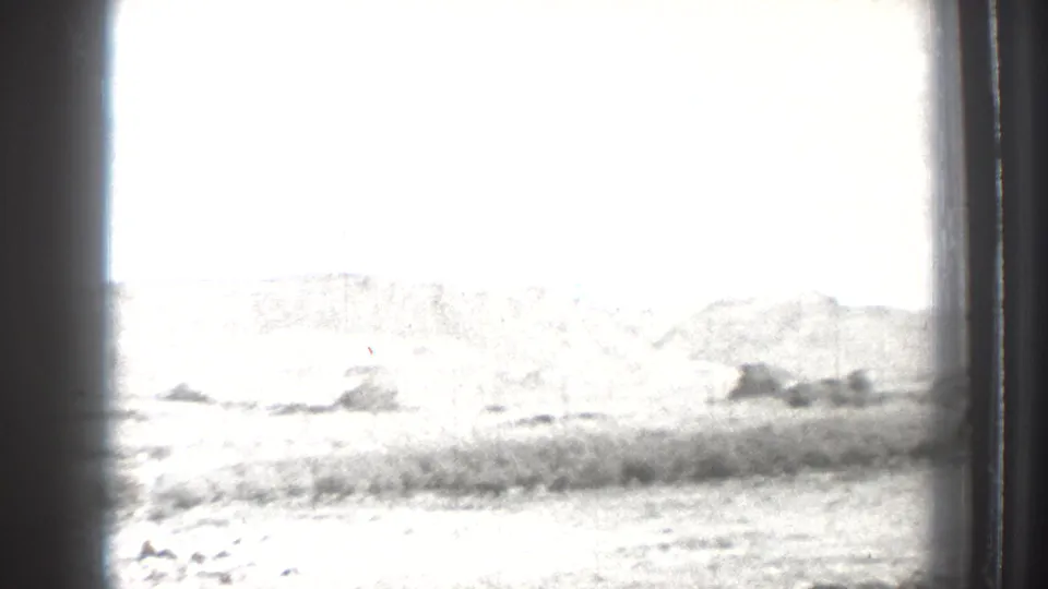 1939 Washington 8mm frame showing a bright lakeside landscape with scrub and distant hills, partly obscured by the film or window edge.