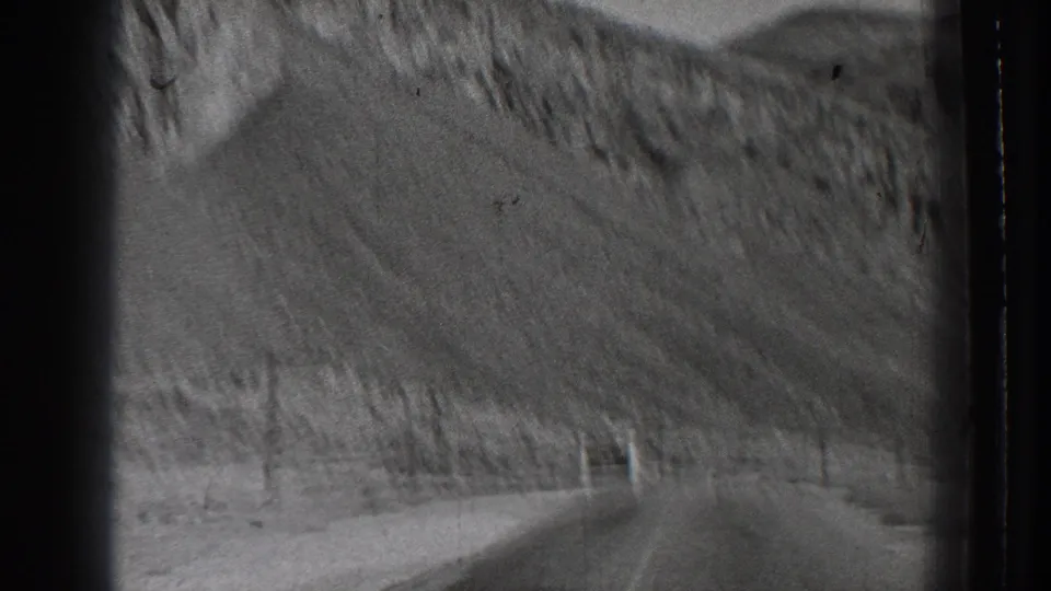 1939 Washington home-movie view from a moving vehicle on a road through steep, sparsely vegetated hills.