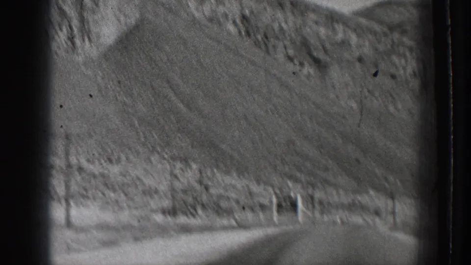 Home-movie driving view of a mountain road bending past dry brush and a steep hill in Washington, 1939.