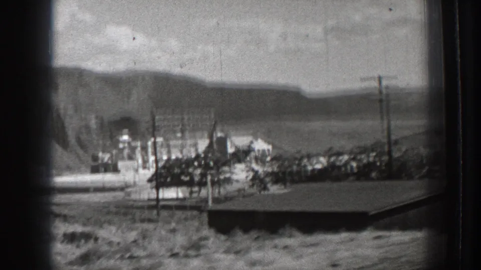 1939 Washington roadside view appears to show a Rock Island Dam sign, industrial structures, utility poles, and hills from a moving vehicle.