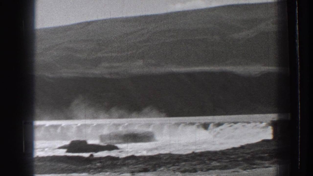 1939 Washington home-movie frame showing rocky waterfront and breaking surf seen through dark train-window framing.