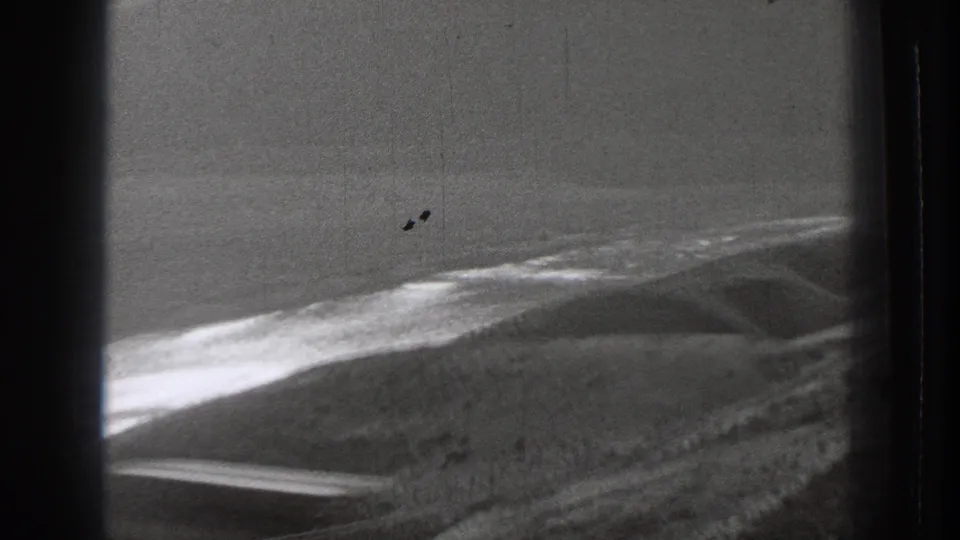 1939 Washington home-movie frame showing a curved shoreline and surf through dark train-window framing.