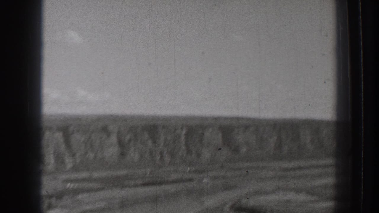 Black-and-white 1939 8mm view of a rugged open landscape in Washington, with distant cliffs and a broad channel or riverbed.
