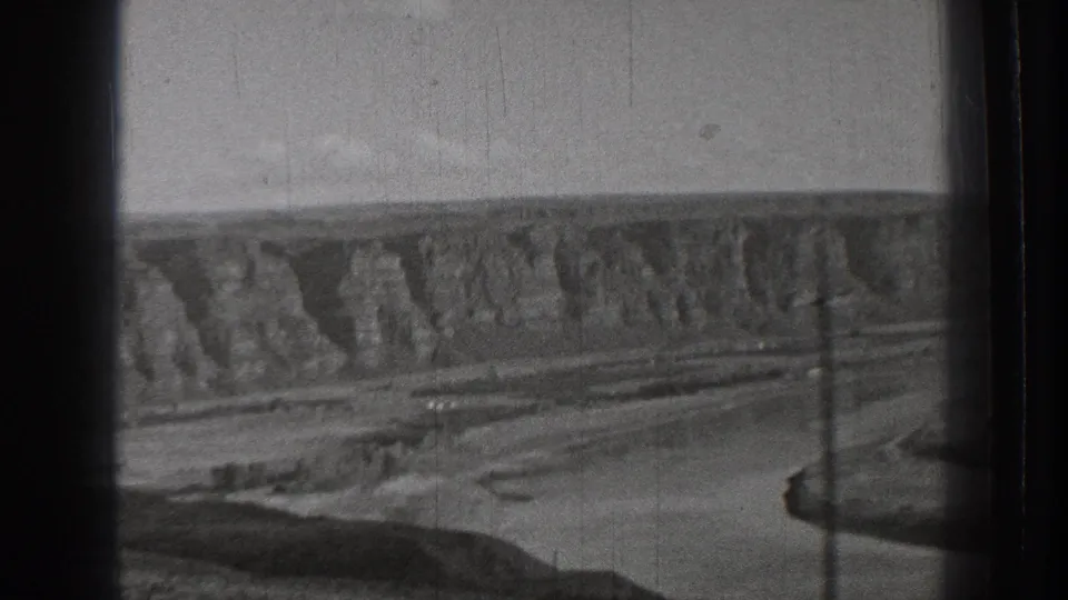 Black-and-white 1939 Washington landscape with cliffs, open ground, utility poles, and a winding river or dry channel.