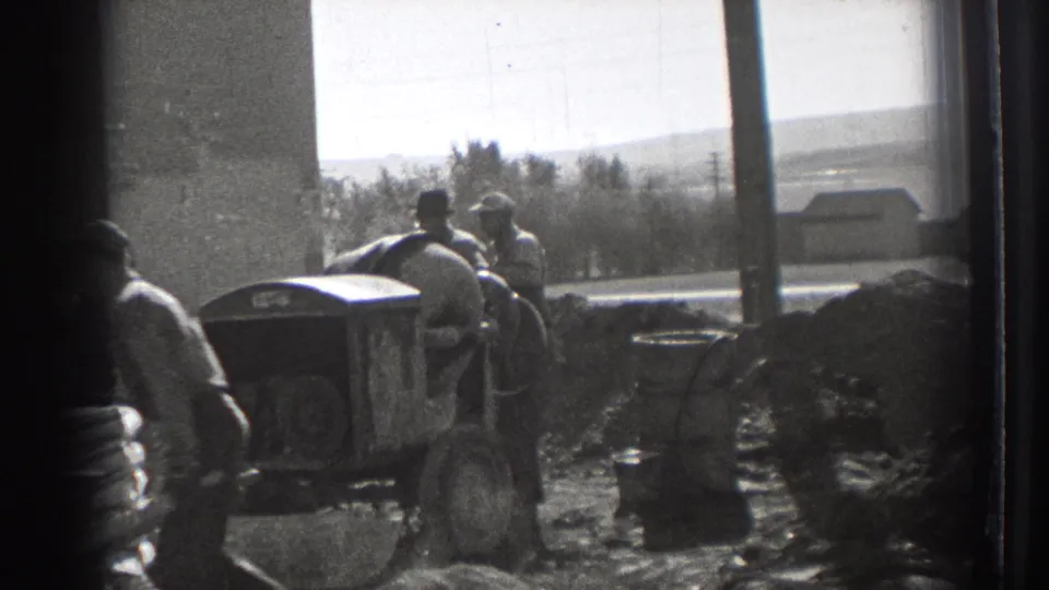 In Washington, 1939, workers gather at a construction site with dirt piles, equipment, and a street visible beyond the building edge.