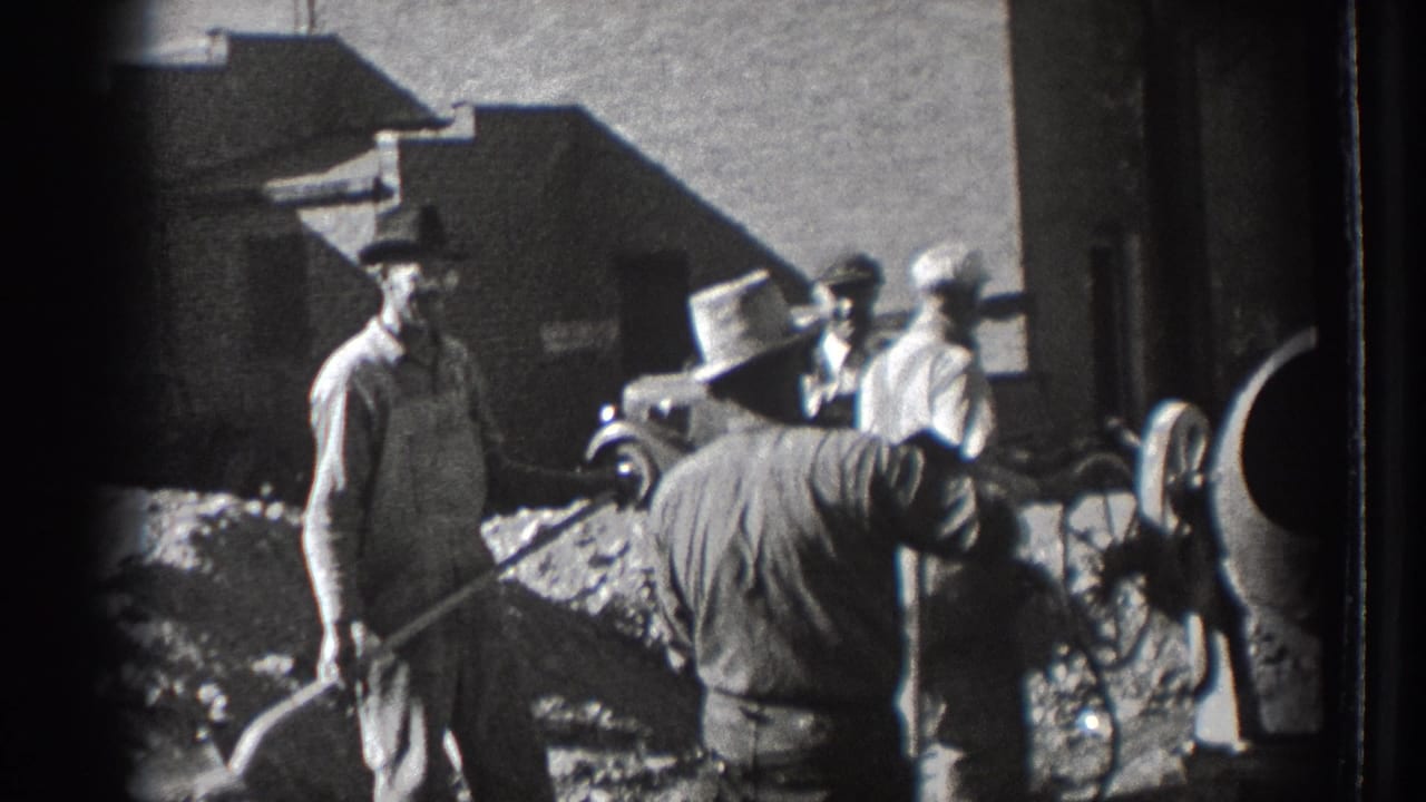 In 1939 Washington footage, adult workers in hats stand near shovels, aggregate, a cement mixer, and a parked vintage car.
