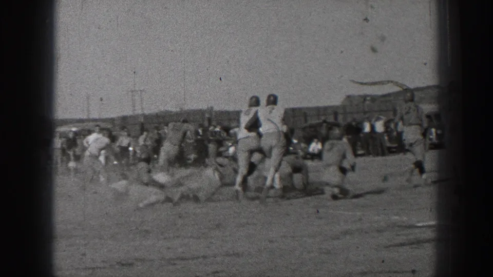 Black-and-white 8mm footage shows a sideline view of football players regrouping around a tackle during a 1939 Washington game.