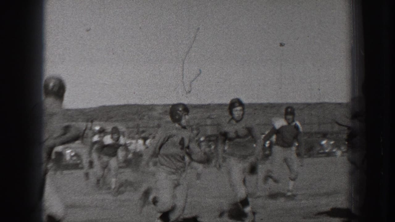 Football players in helmets move across an outdoor field.