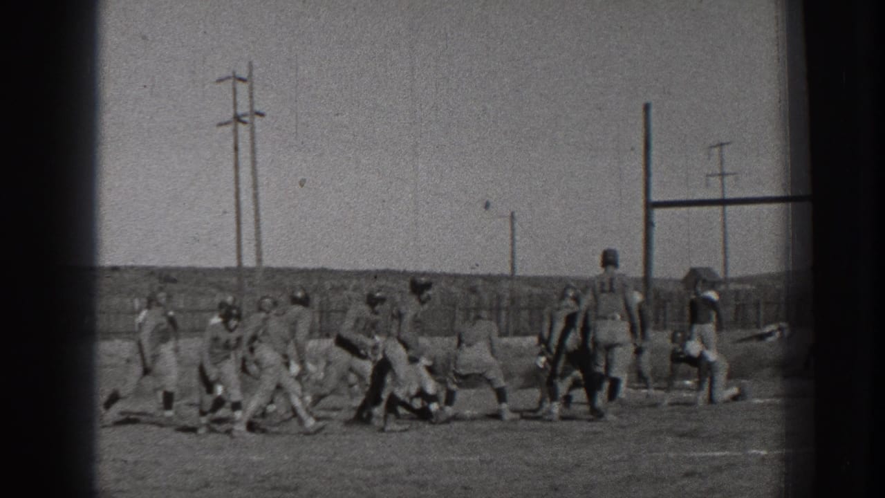 Football players cluster near a line of scrimmage on a field.