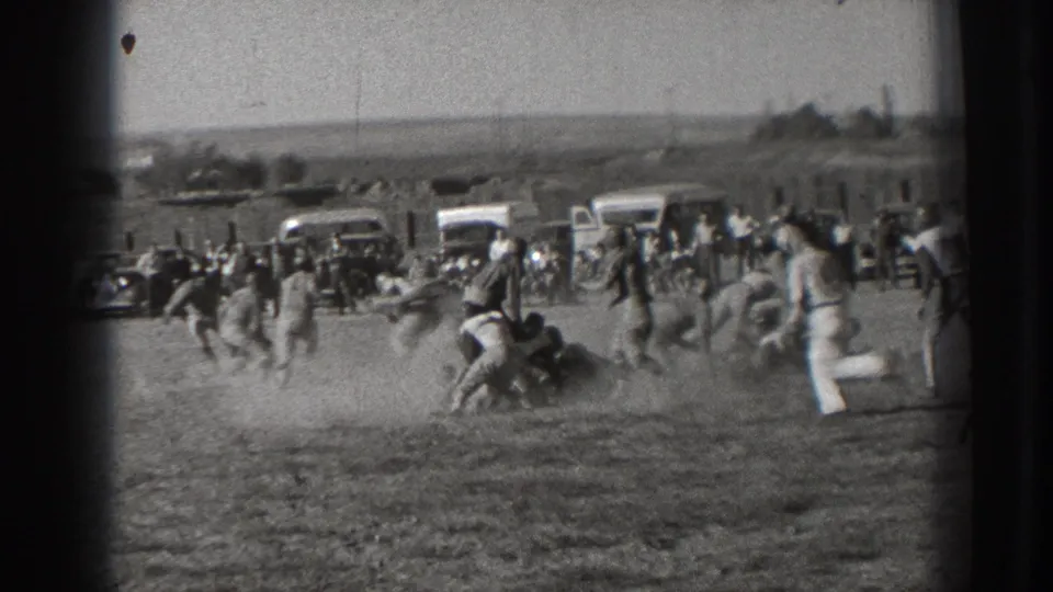 1939 Washington home-movie view of players running during an amateur football game on a dusty open field.