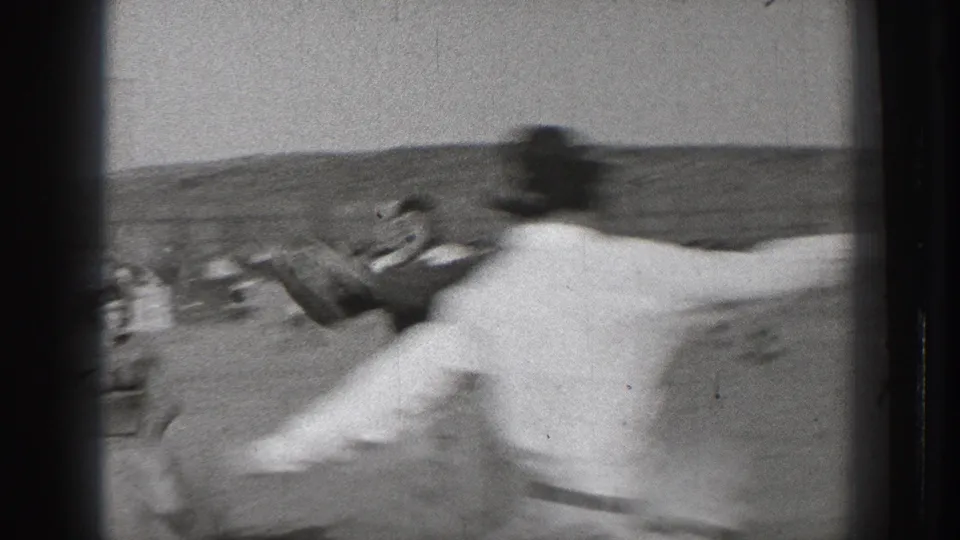 A close, motion-blurred figure crosses the foreground during the 1939 Washington amateur football footage.