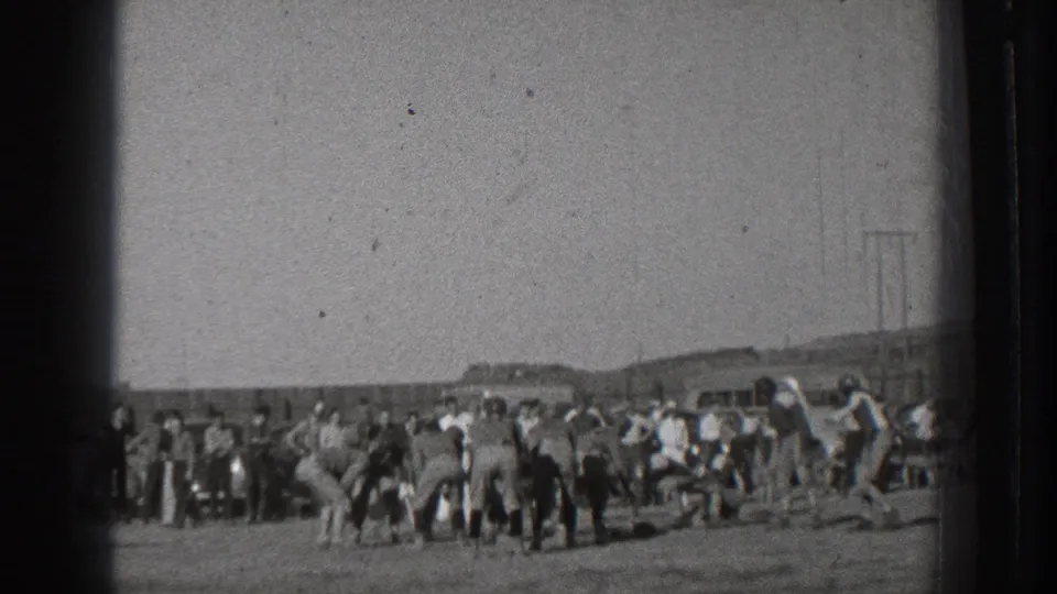 Wide 1939 Washington home-movie frame of an amateur football game, with players on the field and spectators along the boundary.