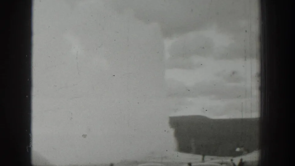 1939 Wyoming 8mm frame showing the geyser eruption through soft focus, with faint spectators and pronounced scratches and dust.